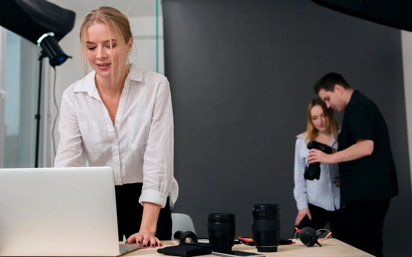 A woman working on a laptop and people viewing photos